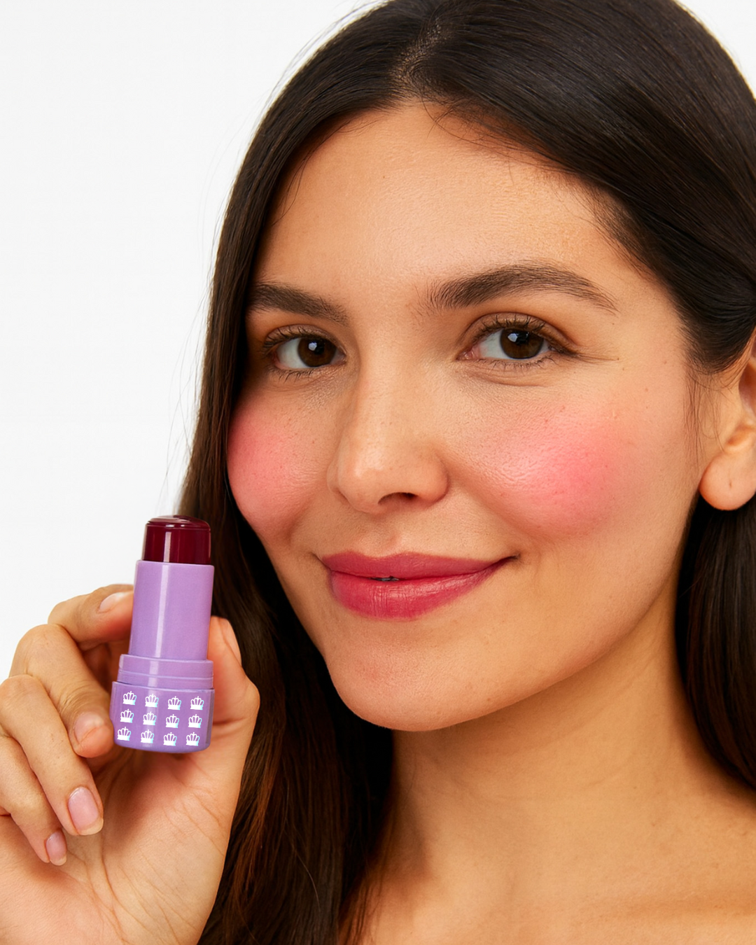 Model holding an open tube of Mo-Beauty Shop's Mo-Jelly Blush + Lip Tint stick in the shade Berry Crush, showing the buildable berry-pink color applied on lips and cheeks, on a white background